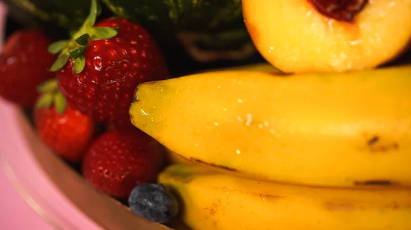 Закрыть спелые бананы возле красной клубники и персика — стоковое фото
