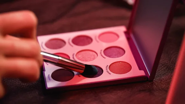 Partial view of woman applying eye shadow on cosmetic brush — Stock Photo