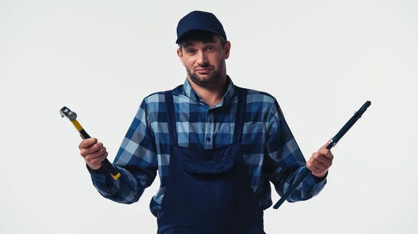 Confused handyman holding tools and looking at camera isolated on white — Stock Photo