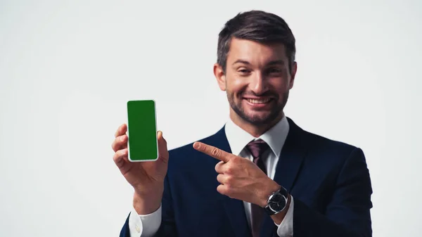 Smartphone con pantalla verde en la mano del empresario borroso apuntando con el dedo aislado en blanco - foto de stock