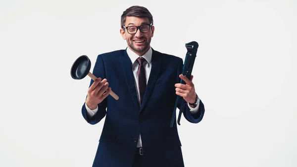 Empresario positivo sosteniendo émbolo y llave de tubo aislado en blanco - foto de stock