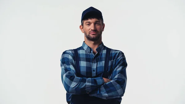 Workman in cap and overalls standing with crossed arms isolated on white — Stock Photo