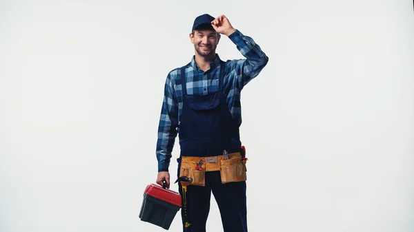 Cheerful repairman with toolbox holding cap isolated on white — Stock Photo