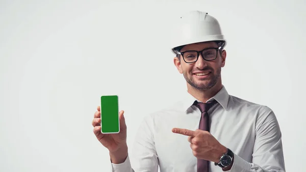 Arquiteto em capacete apontando para o telefone celular com chave chroma isolado no branco — Fotografia de Stock