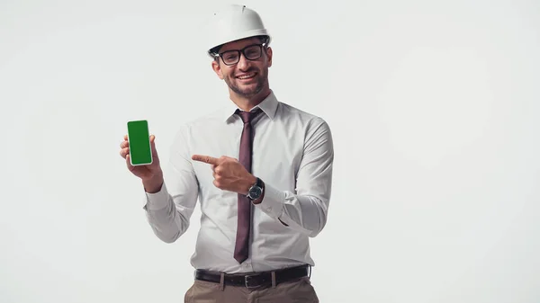 Веселий інженер вказує на смартфон з ключем хроми ізольовано на білому — стокове фото