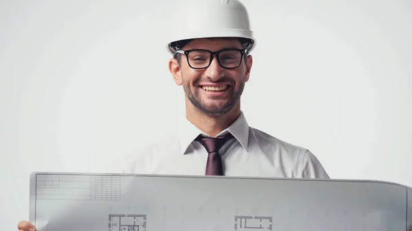 Happy engineer in hardhat holding blurred blueprint isolated on white — Stock Photo