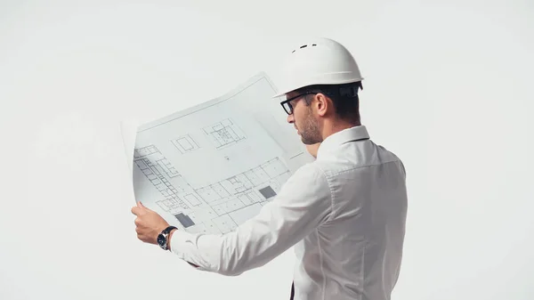 Инженер в шлеме смотрит на чертеж, изолированный на белом — стоковое фото