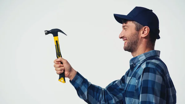 Vista lateral de obrero alegre sosteniendo martillo aislado en blanco - foto de stock