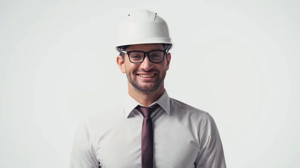 Arquitecto en camisa, anteojos y hardhat sonriendo a cámara aislada en blanco - foto de stock