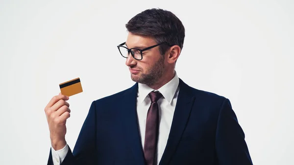 Businessman in formal wear and eyeglasses looking at credit card isolated on white — Stock Photo