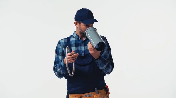 Handyman en overoles mirando tubo de plástico aislado en blanco - foto de stock