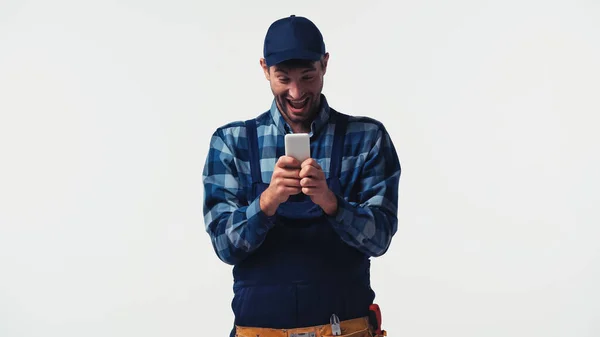 Excited handyman using smartphone isolated on white — Stock Photo