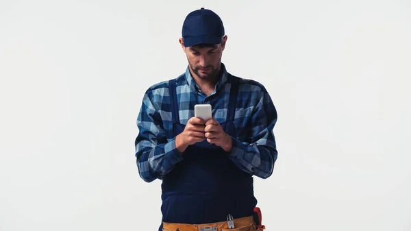 Foreman in tool belt using smartphone isolated on white — Stock Photo