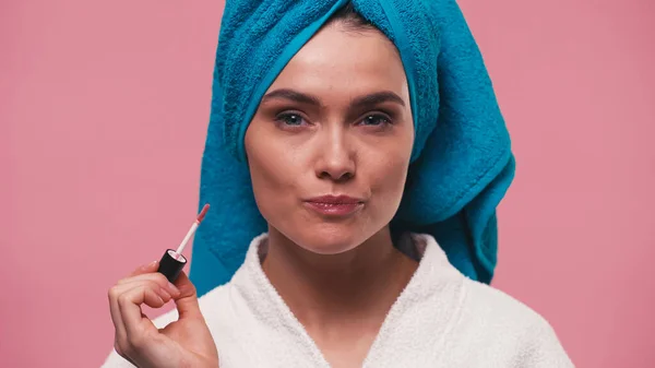 Mulher com maquiagem natural e toalha na cabeça segurando brilho labial isolado em rosa — Fotografia de Stock