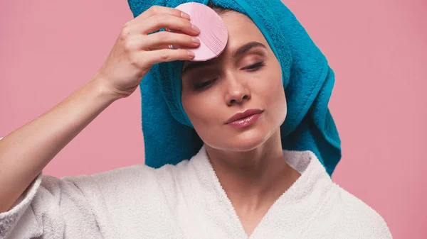 Young woman using electric silicone cleanser on face isolated on pink — Stock Photo