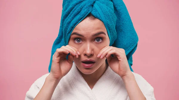 Junge Frau mit Frotteehandtuch auf dem Kopf berührt Gesicht isoliert auf rosa — Stockfoto