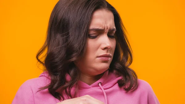 Displeased woman feeling disgusted while feeling stinky smell isolated on yellow — Stock Photo