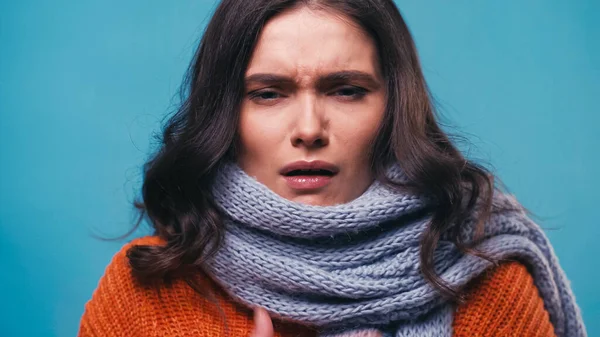 Sick woman in warm scarf suffering from pain in sore throat isolated on blue — Stock Photo