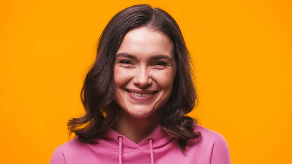 Pleased brunette woman smiling at camera isolated on yellow — Stock Photo