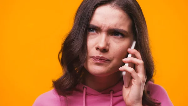 Worried woman talking on mobile phone isolated on yellow — Stock Photo