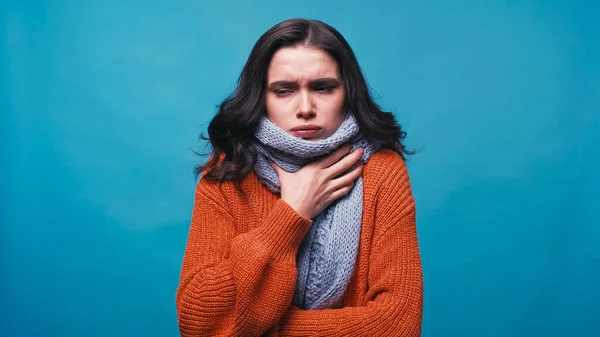 Femme malade en écharpe chaude toucher le cou tout en souffrant de douleur dans la gorge isolé sur bleu — Photo de stock