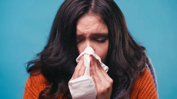 Mulher doente com olhos fechados espirrando em guardanapo de papel isolado em azul — Fotografia de Stock