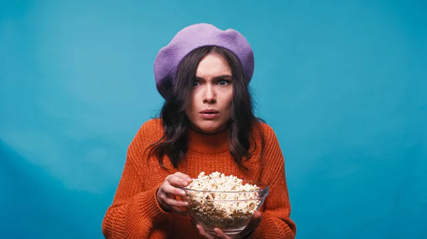 Femme impressionnée avec popcorn regarder film à couper le souffle isolé sur bleu — Photo de stock