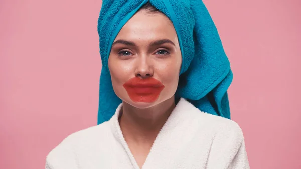 Woman with lip mask and terry towel on head looking at camera isolated on pink — Stock Photo