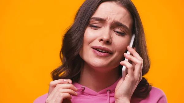 Cheerful woman in pink hoodie talking on mobile phone isolated on yellow — Stock Photo