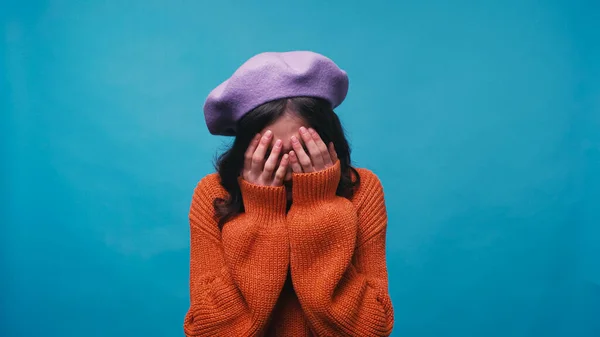 Frustrata donna che copre il viso con le mani mentre piange isolato su blu — Foto stock