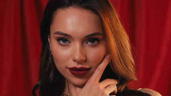 Hermosa mujer joven con lápiz labial brillante mirando a la cámara en rojo - foto de stock