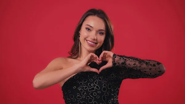 Feliz joven mostrando el signo del corazón con las manos aisladas en rojo - foto de stock