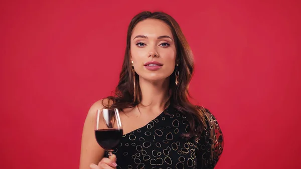Elegante junge Frau mit einem Glas Wein auf rotem Grund — Stockfoto