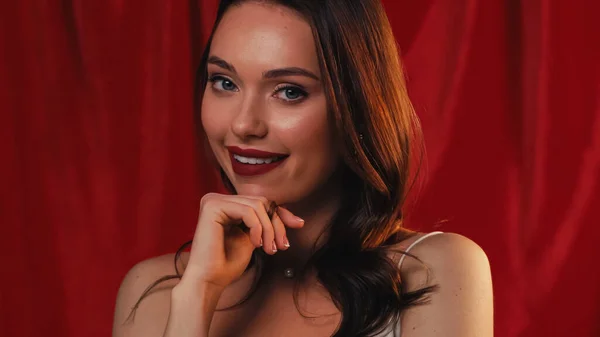 Кокетливая молодая женщина улыбается в камеру на красный — стоковое фото