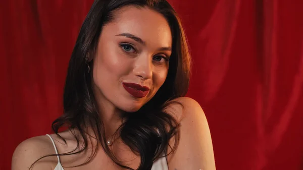Flirty Frau lächelt und blickt in die Kamera auf rot — Stockfoto