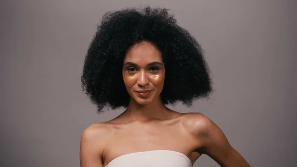 Pleased african american woman with bare shoulders and eye patches isolated on grey — Stock Photo
