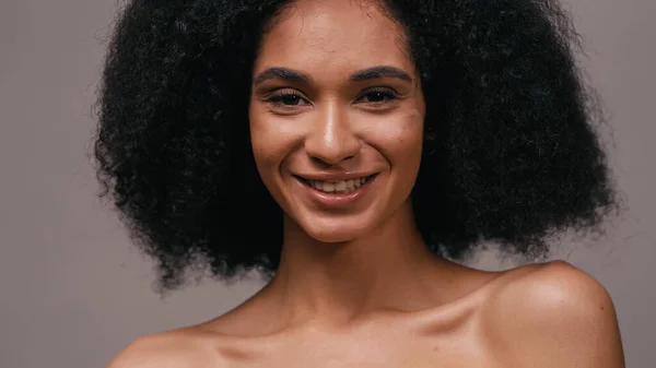 Sonriente mujer afroamericana con hombros desnudos aislados en gris - foto de stock