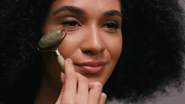 Gros plan de jeune femme afro-américaine en utilisant un rouleau de jade — Photo de stock