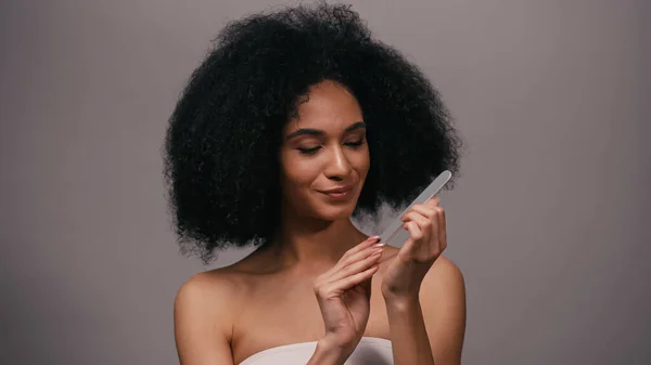 Piacere giovane donna afroamericana utilizzando lima per unghie isolato su grigio — Foto stock