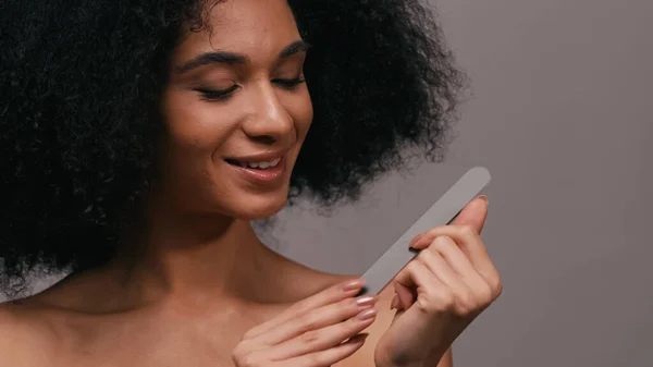 Femme afro-américaine gaie utilisant lime à ongles isolé sur gris — Photo de stock