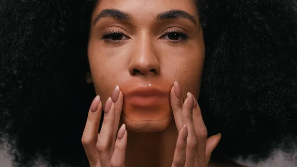Close up of young african american woman applying collagen lip patch — Stock Photo