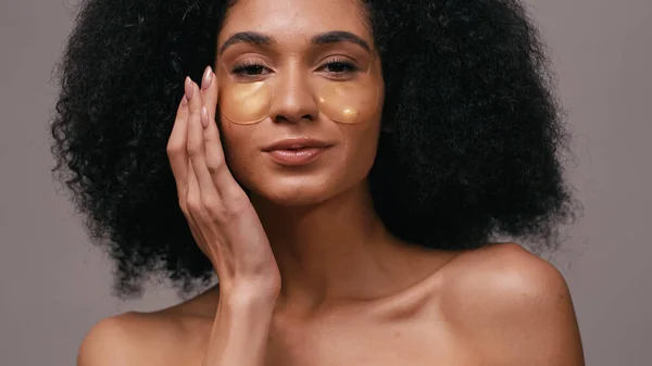 Close up de mulher afro-americana aplicando manchas olho hidrogel isolado em cinza — Fotografia de Stock