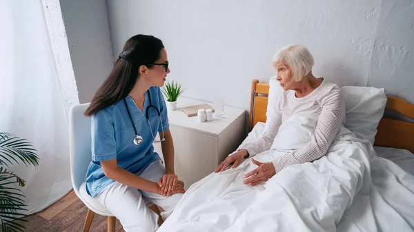 Enfermera joven y anciana hablando en la clínica - foto de stock