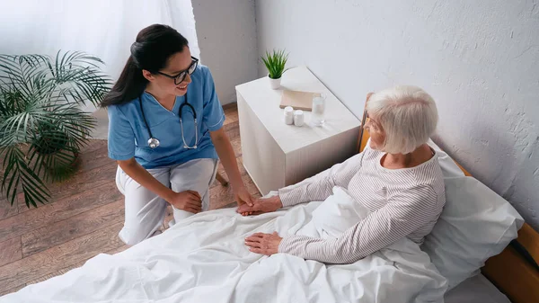 Високий кут зору щасливої медсестри в окулярах і літньої жінки, що розмовляє в клініці — стокове фото