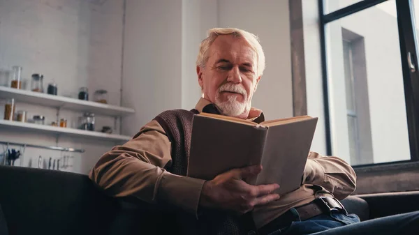 Barbudo sênior leitura livro em casa — Fotografia de Stock