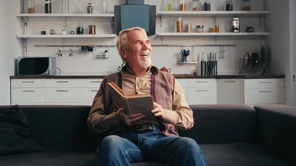 Feliz hombre mayor sosteniendo libro en casa - foto de stock