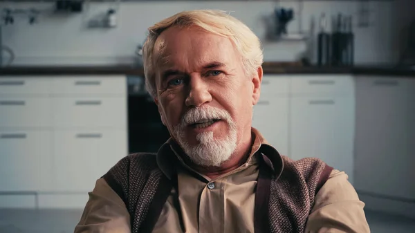 Bearded pensioner talking while looking at camera — Stock Photo