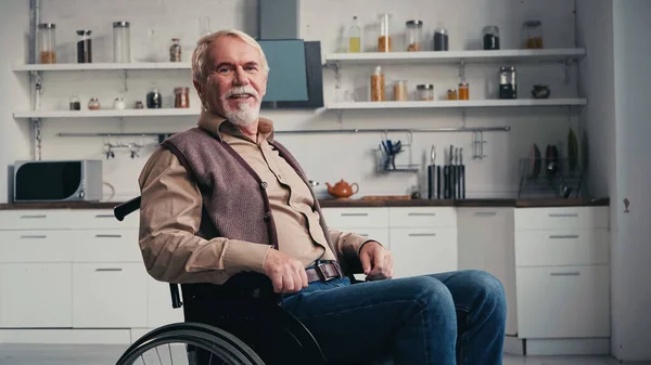 Pensionné handicapé souriant assis en fauteuil roulant — Photo de stock