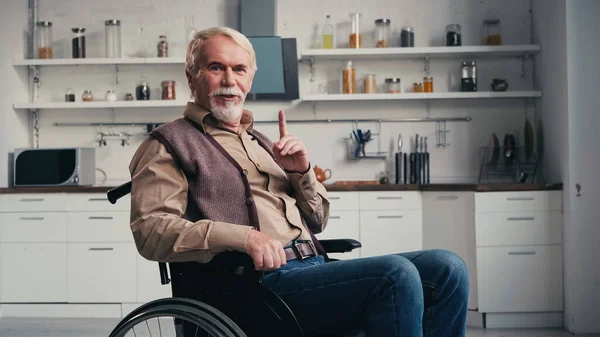 Handicapped pensioner pointing with finger while sitting in wheelchair — Stock Photo