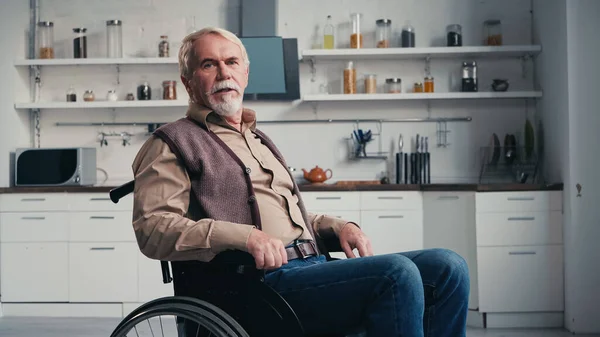 Disabled pensioner looking at camera while sitting in wheelchair — Stock Photo